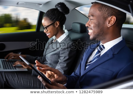 Stock fotó: Two Businesspeople Sitting Inside Car Using Electronic Devices