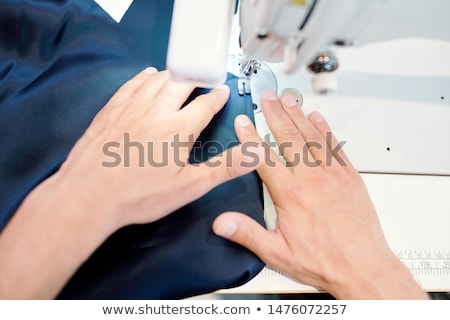 Human Hands Holding Dark Blue Fabric While Sewing By Machine Foto stock © Pressmaster