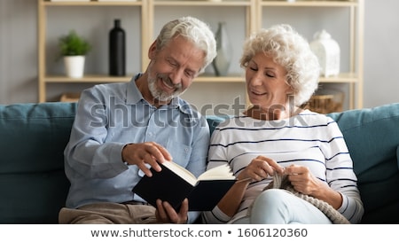 Stok fotoğraf: Smiling Attractive Elderly Woman Reading In A Book And Making A