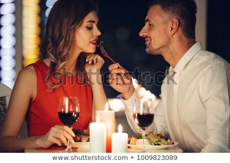 [[stock_photo]]: Smiling Careful Man Feed His Pretty Girlfriend While Have Romantic Dinner At Home