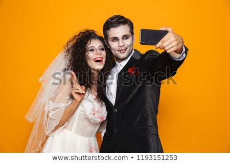 Stok fotoğraf: Pretty Creepy Man And Woman In Wedding Costumes Making Selfie On Smartphone Isolated