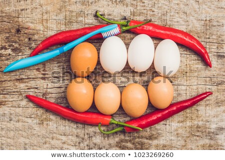 Foto stock: Eggs And Red Pepper In The Form Of A Mouth With Teeth White Eggs Are Bleached Teeth Yellow Eggs  