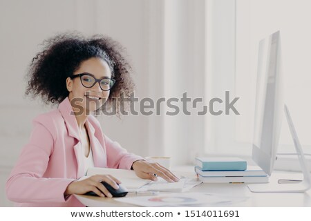 Zdjęcia stock: Prosperous Curly Female Entrepreneur Checks Documents Studies Contract Works On Computer Wears Gl