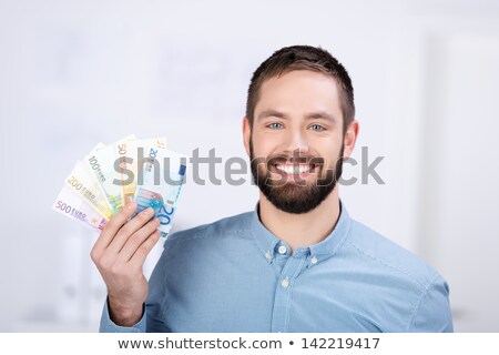 Stok fotoğraf: Smiling Businessman Holding A Handful Of Banknotes
