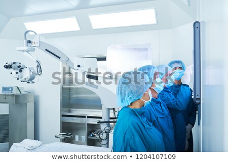 Stockfoto: Surgeons Interacting With Monitor In Operating Theatre