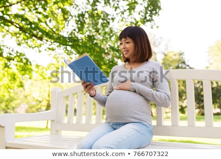 Stock foto: Happy Pregnant Asian Woman Reading Book At Park