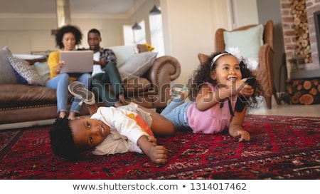 Stock fotó: Side View Of Happy African American Sibling Lying On Floor And Watching Television While Parents Usi