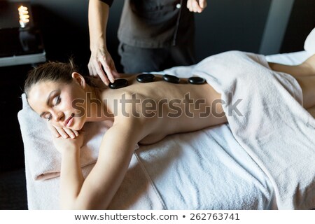 Foto stock: Masseur Placing Hot Stones Onto A Young Beautiful Ladys Back