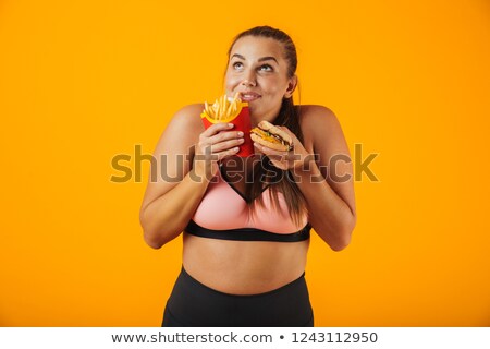 Foto stock: Image Of Cheerful Chubby Woman In Tracksuit Eating Sandwich And