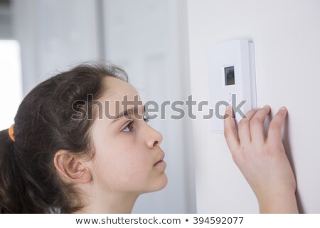 Stock fotó: Teen Adjusting Thermostat On Central Heating Control