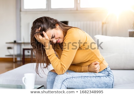 Woman Suffering From Stomachache On Sofa Zdjęcia stock © Photoroyalty