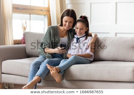 [[stock_photo]]: Two Beautiful Young Woman Sitting On Sofa With Game Controller