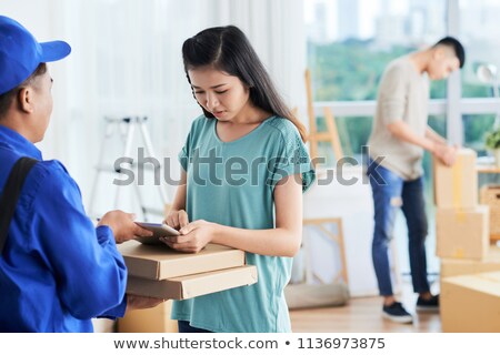 Foto stock: Female Putting Signature To Pizza Courier Tablet