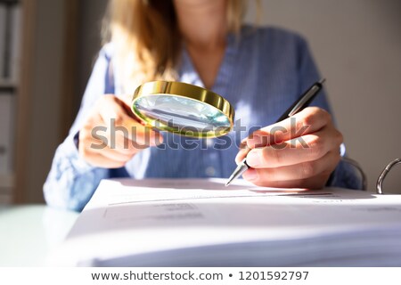 Stock fotó: Woman Holding Magnifying Glass Over Invoice