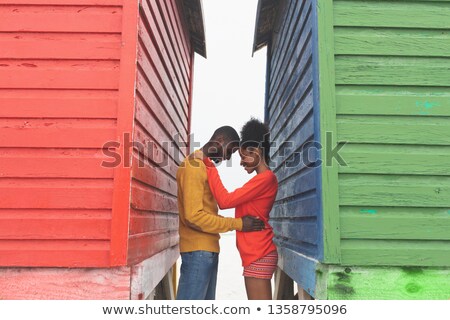 ストックフォト: Side View Of Romantic Multi Ethnic Couple Embracing Each Other Between Beach Huts At Beach