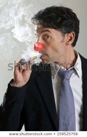 Stock fotó: Man In A Red Nose Puffing On An E Cigarette