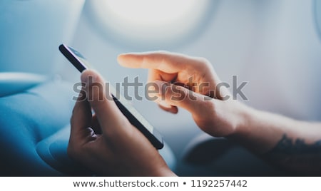 Stock fotó: Persons Hand Using Mobile Phone In Airplane