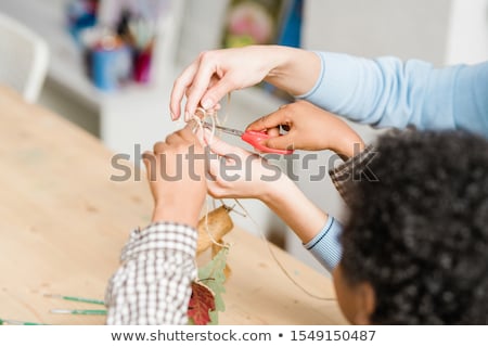 Foto d'archivio: Hands Of Young Teacher Holding Stick With Decorations Hanging On Threads