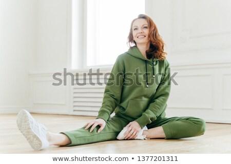 Stock fotó: Athletic Woman Stretches Leg Has Satisfied Facial Expression Wears Black Clothes White Sportshoes