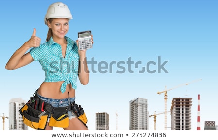 Foto stock: Smiling Young Woman In Hard Hat Holding Calculator