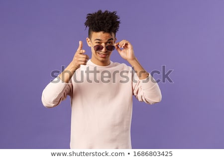 Stock photo: Portrait Of Young Handsome Smiling Guy With Sunglasses Showing Gesture With Open Arms On Yellow Back