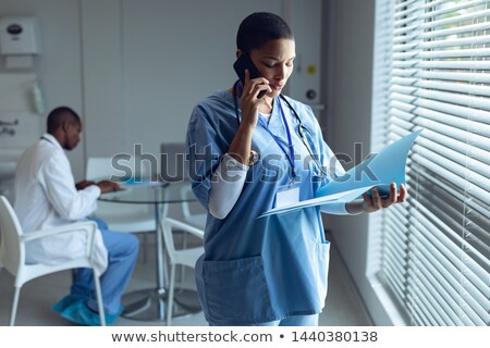 Stock photo: Side View Of Matured Mixed Race Female Doctor Interacting And Examining Caucasian Girl Hand In Clin