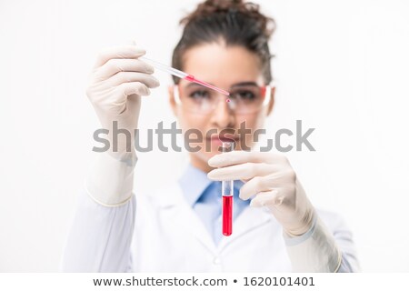 Stockfoto: Hands Of Clinician Dropping Red Liquid Substance Into Flask With New Vaccine