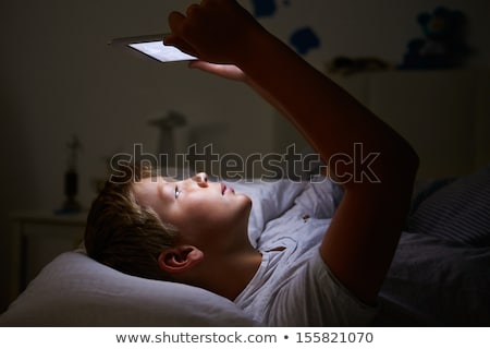 Foto stock: Boy Looking At Digital Tablet In Bed At Night