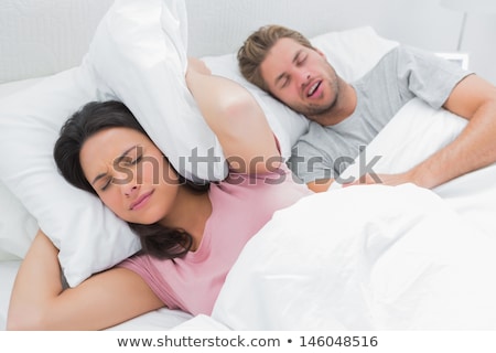 Foto stock: Woman Covering Her Ears While Her Husband Snoring On Bed