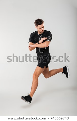 Stockfoto: Smiling Young Sportsman Listening To Music With Earphones