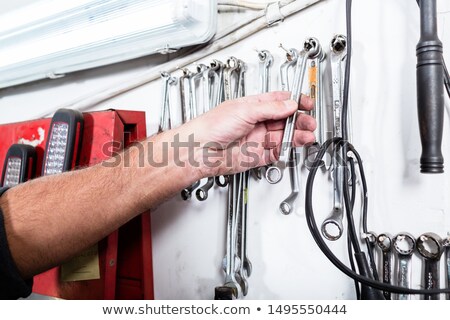 Stock photo: Auto Mechanic Taking Spanner From The Wall