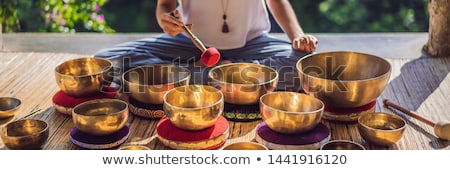Stock photo: Woman Playing On Tibetan Singing Bowl While Sitting On Yoga Mat Against A Waterfall Vintage Tonned