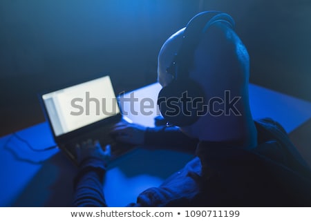 Foto stock: Hacker With Microphone And Laptop In Dark Room