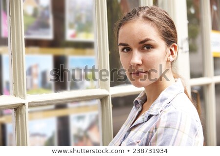 Foto d'archivio: Disappointed Young Woman Looking In Window Of Estate Agents