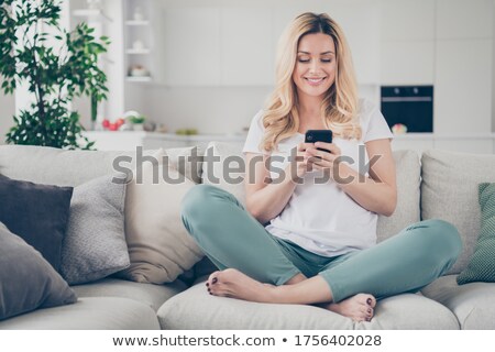 Foto stock: Smiling Blond Woman Sending A Text Lying On The Floor