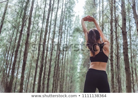 [[stock_photo]]: Young Woman Stretching And Breathing Fresh Air In Middle Of Fore