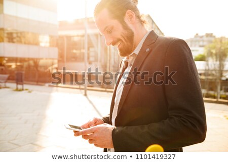 Foto stock: Photo Of Sunlit Pleased Man In Formal Suit Smiling And Holding S