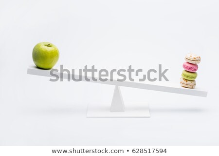 Foto d'archivio: Close Up View Of Apple And Macarons Balancing On Seesaw Healthy Living Concept