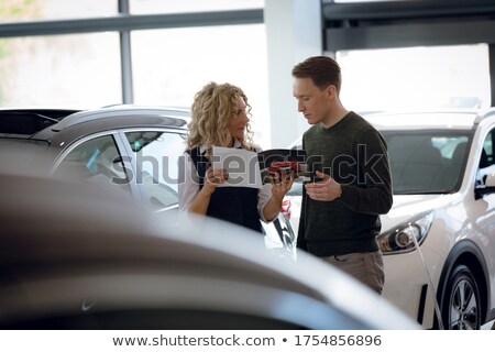 Foto d'archivio: Saleswoman Holding Brochure While Standing With Customer