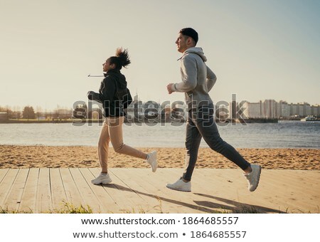 Stock fotó: Couple In Sports Clothes Running Along On Beach