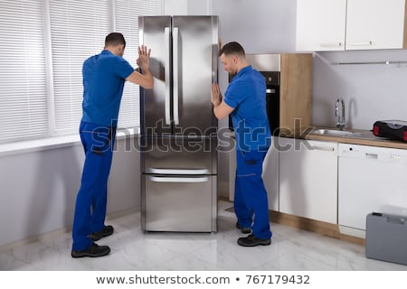 [[stock_photo]]: Young Male Mover Carrying Home Appliances In Kitchen
