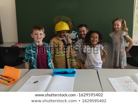 Stock photo: Front View Happy Male Firefighter With Schoolkids Looking At Camera And One Of Them Has Got Firefigh