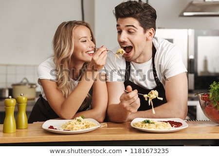 Stock photo: Excited Young Friends Loving Couple Chefs On The Kitchen Eat Tasty Pasta