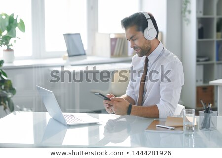 ストックフォト: Elegant Office Worker In Headphones Looking Through Playlist