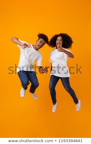 Stock fotó: Cute African Couple Jumping Isolated Over Yellow Background