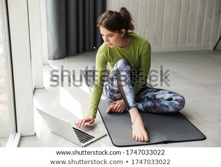 Stock foto: Photo Of Focused Sportswoman Using Laptop While Working Out On Mat