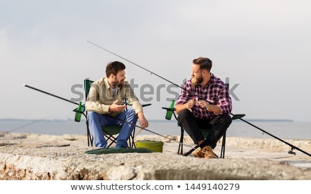 Stockfoto: Friends Adjusting Fishing Rods With Bait On Pier