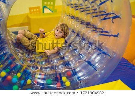 Сток-фото: Cute Little Boy Playing In Zorb A Rolling Plastic Cylinder Ring With A Hole In The Middle Intdoor