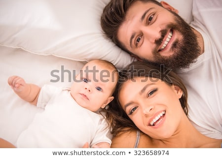 Сток-фото: Portrait Of Happy Young Parents With Baby In The Bed At Home