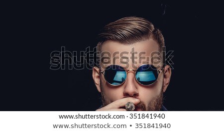 Foto stock: Bearded Man With Sunglasses Smoking A Cigar